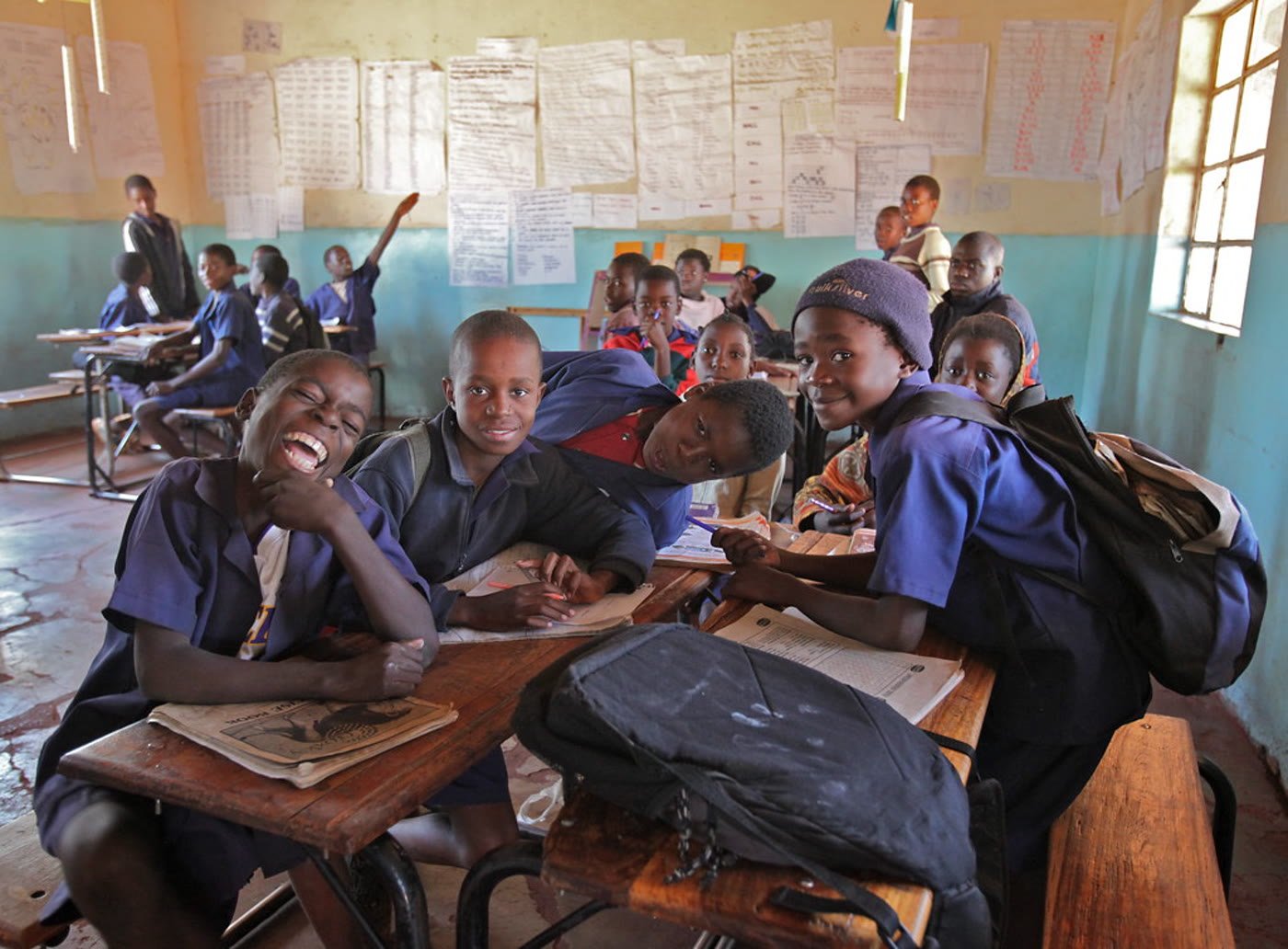 Children joyfully raising their hands in a sunlit classroom