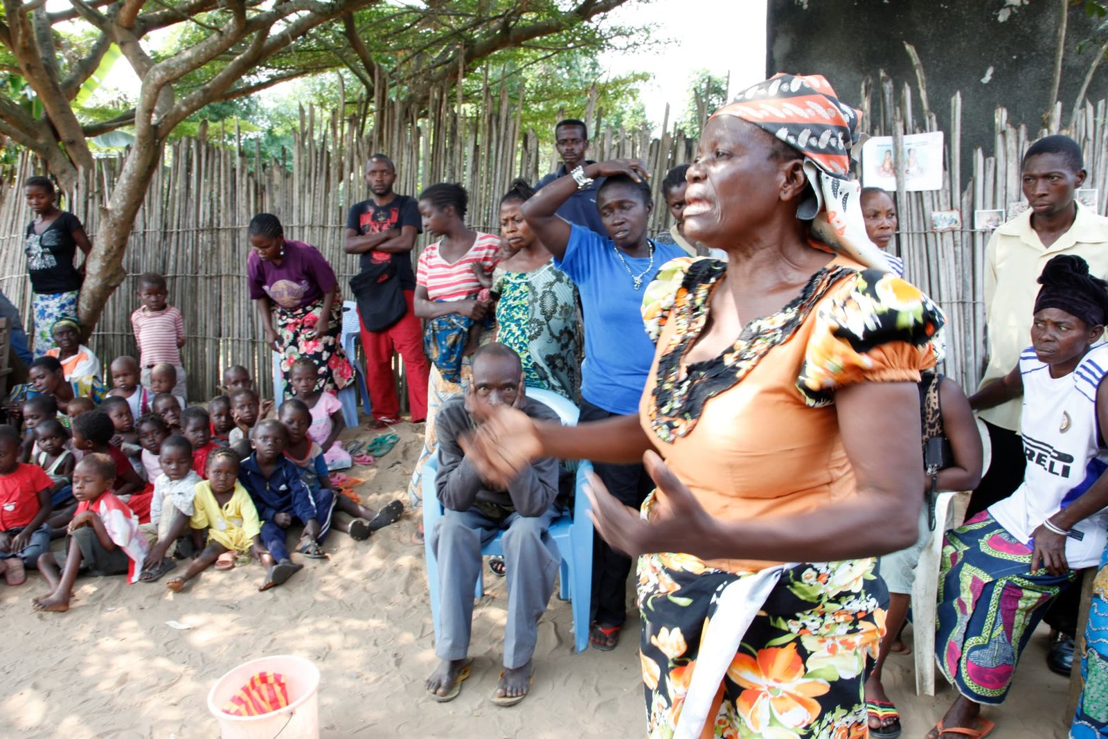 A respected community elder speaking with families gathered together outdoors